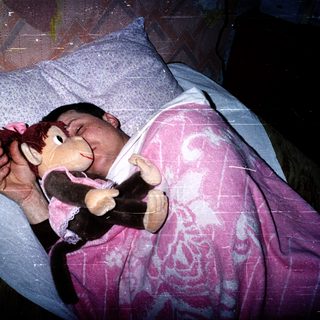 Child sleeping peacefully with stuffed monkey toy.