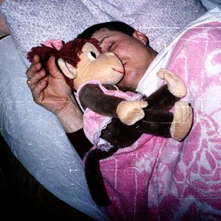 Child sleeping peacefully with stuffed monkey toy.