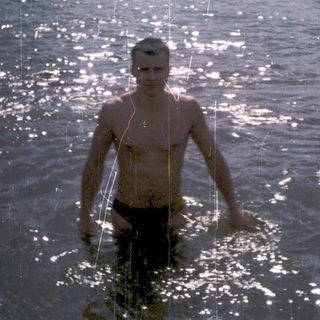 Shower of water streams over two people swimming outdoors.