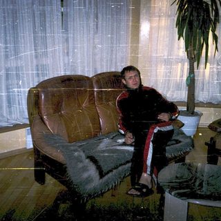 Person sitting on a couch indoors during snowfall.