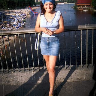 Woman smiling by waterfront during light rain.