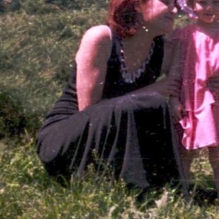 Three people sitting together outdoors in vintage clothing.