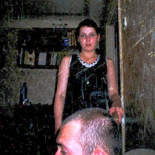 Woman standing in shower with man looking up.