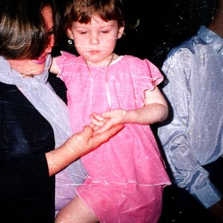 Child being held by adult during water play.