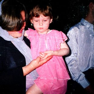 Child being held by adult during water play.