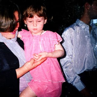Child being held by adult during water play.