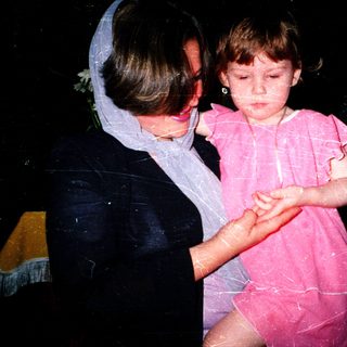 Child being held by adult during water play.