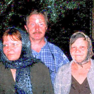 Three people standing outdoors at night in rain.