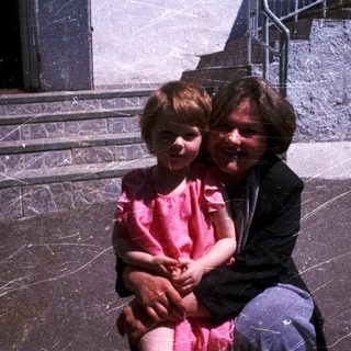 A woman and young child sitting together outdoors.