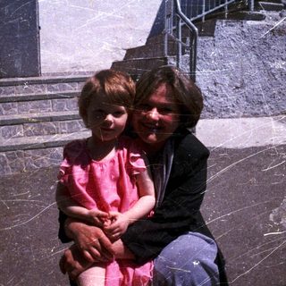 A woman and young child sitting together outdoors.