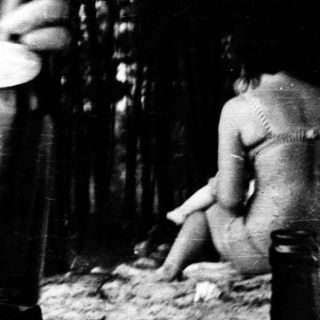 Woman cooking outdoors in natural setting.