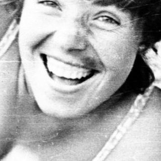 Woman smiling while lying on beach towel.