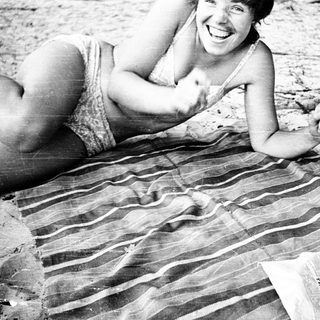 Woman smiling while lying on beach towel.