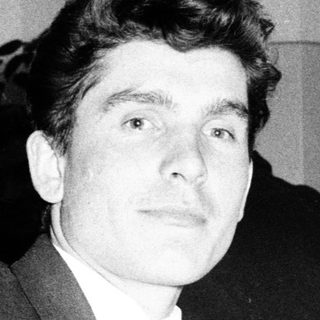 Young man in suit at formal event with cameras.