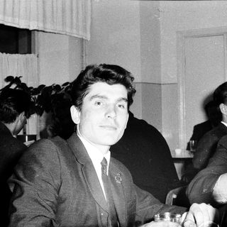 Young man in suit at formal event with cameras.