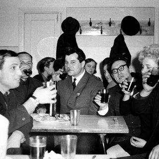 Group of people in formal attire drinking and dining together.