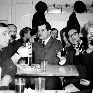 Group of people in formal attire drinking and dining together.