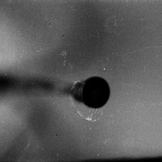 Drill bit creating hole in metal surface.