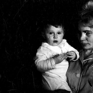 A person holding a crying baby in dim lighting.