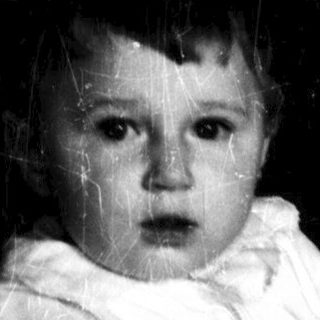 A person holding a crying baby in dim lighting.
