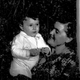 A baby and adult in vintage-style photo, holding hands through a reflective surface.