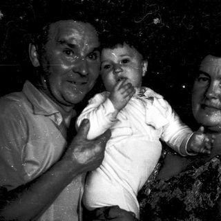 A wet, joyful family moment with grandparents holding a baby.