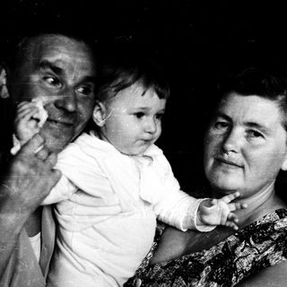 Tender moment of elderly couple holding baby indoors.