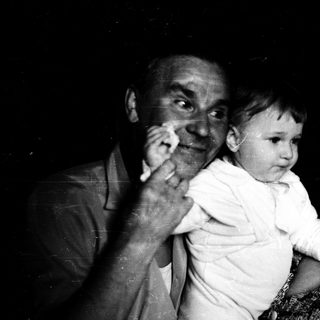 Tender moment of elderly couple holding baby indoors.