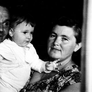 Tender moment of elderly couple holding baby indoors.