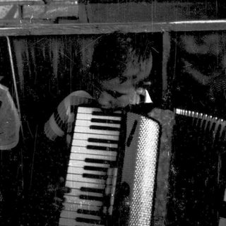 Person playing accordion indoors near brick wall.