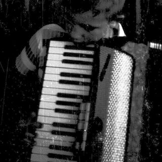 Person playing accordion indoors near brick wall.