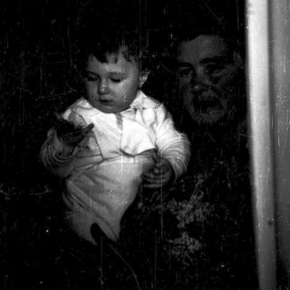 A young child standing near a window.