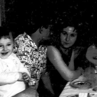 Family gathering with adults and a laughing child indoors.