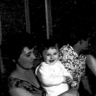 Family gathering with adults and a laughing child indoors.