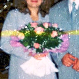Couple posing with flowers at wedding ceremony entrance.