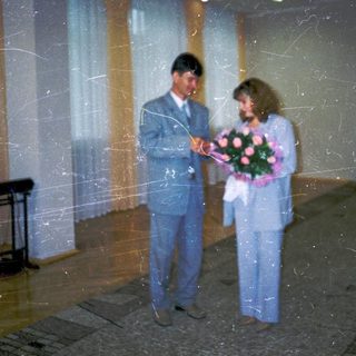 Couple holding bouquet at formal indoor event.
