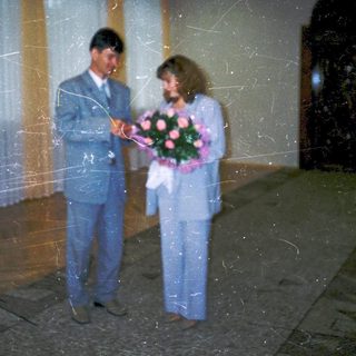 Couple holding bouquet at formal indoor event.