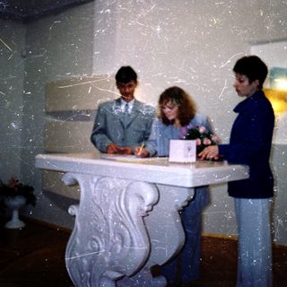Three people signing documents at a registration desk.