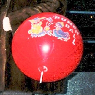 Woman holding red balloon with child near bridge.