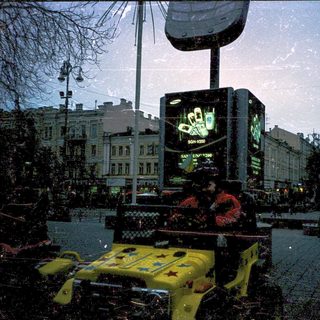 Street vendor selling phones in rainy city square.
