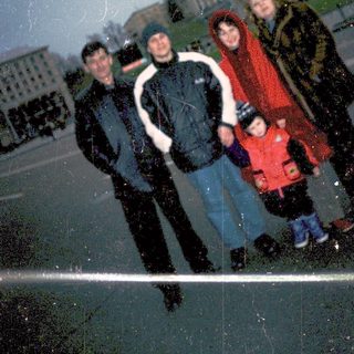Family posing in snowy city square.