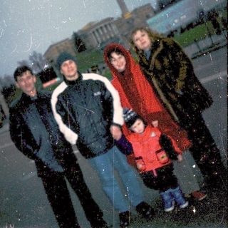 Family posing in snowy city square.