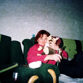 Two people sitting on green theater seats, eating popcorn.
