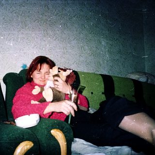 Two people sitting on green theater seats, eating popcorn.