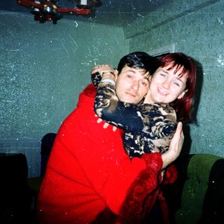 Two people hugging indoors, smiling for a photo.