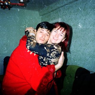 Two people hugging indoors, smiling for a photo.