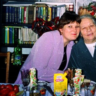 Two women smiling at a festive indoor gathering.
