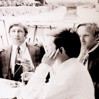 Group of people socializing outdoors at a table.