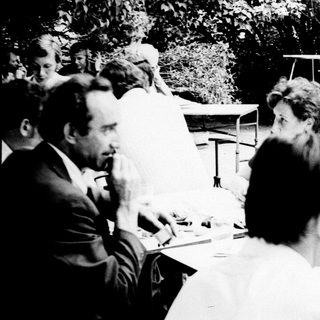 Group gathered outdoors at a table, engaged in conversation.
