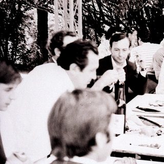 Group gathered around a table at an outdoor social event.
